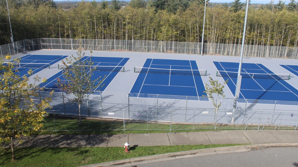 Photo of blue and grey new tennis courts at Squalicum High School, taken from above courts in parking lot
